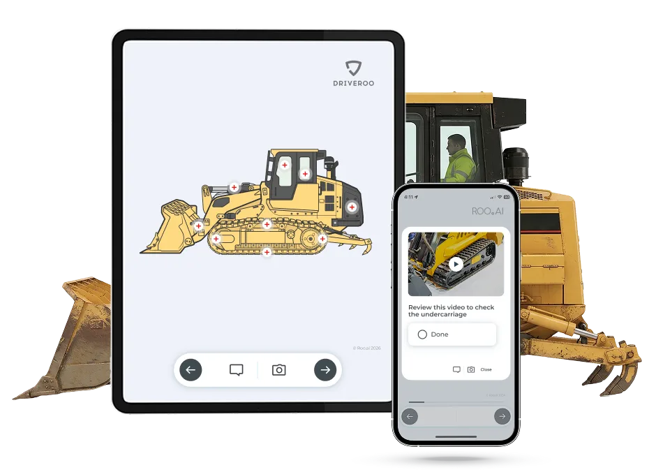 Tablet showing a Driveroo track loader diagram with tappable inspection points, and a phone playing a how-to video for checking the undercarriage, in front of a track loader