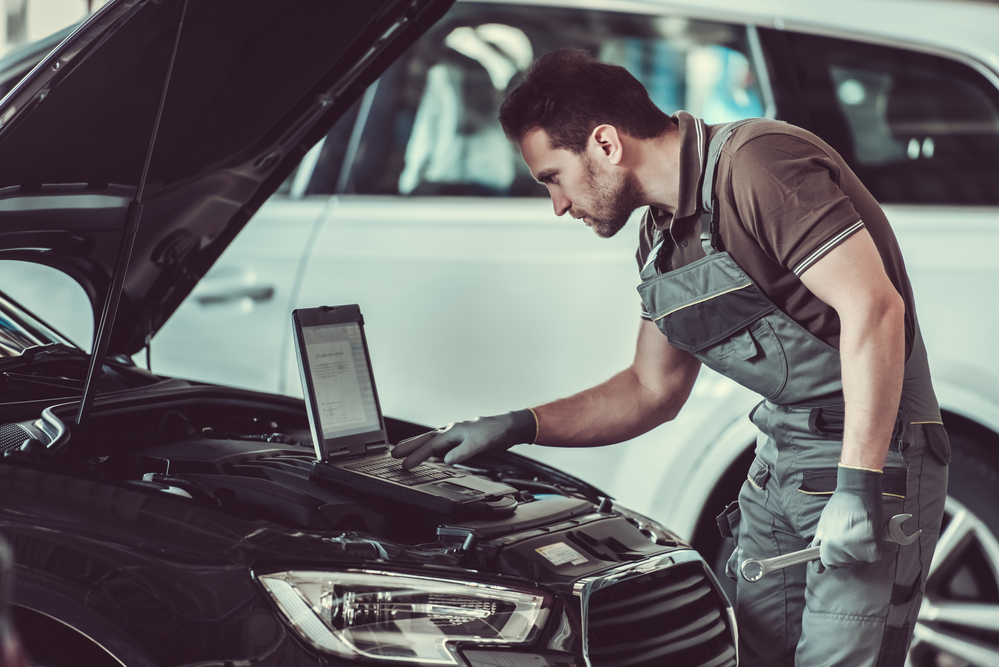 mechanic is using a laptop while repairing car in auto service